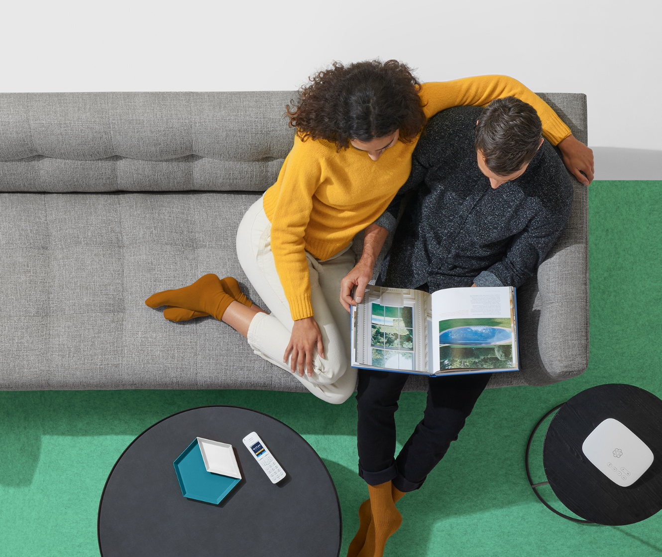 An image of a couple sitting down on sofa, telo handset on the side table